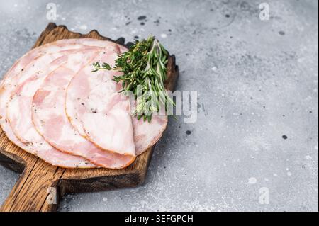 Traditional deli meat (Pancetta) and serving fork on a minimal grey background, perfect for a clean menu design Stock Photo