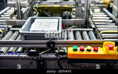 Automated roller conveyor system transferring plastic crate with products in factory, industrial automation logistics. Stock Photo
