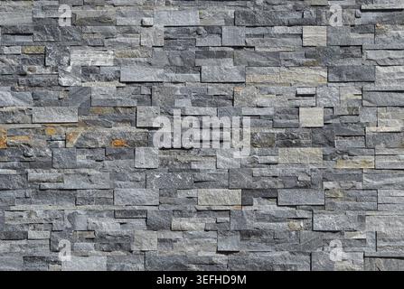 Grey stone wall cladding made of strips and square blocks stacked . Background and texture. Stock Photo