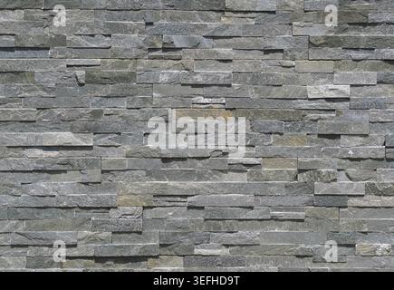 Stone wall cladding made of gray shades strips of rock . Background and texture Stock Photo