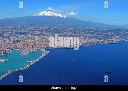 Catania port and city with snow-capped Mount Etna smoking in the background, Taormina , Sicily, Italy. Stock Photo