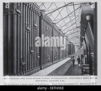 Large vintage economizers and boilerroom equipment at Spreckels Beet Sugar Refinery in Salinas, two workers walking through. THE PLANNING AND CONSTRUCTION OF THE POWER PLANT. By A. E. Dixon. Part IV. WATER SUPPLY AND ITS PURIFICATION. From The Engineering Magazine Devoted to Industrial Progress Volume XXXII October 1906 - March 1907 The Engineering Magazine Co Stock Photo