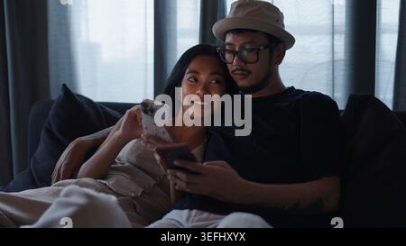 Couple relaxing on sofa, using smartphones together and connecting online Stock Photo
