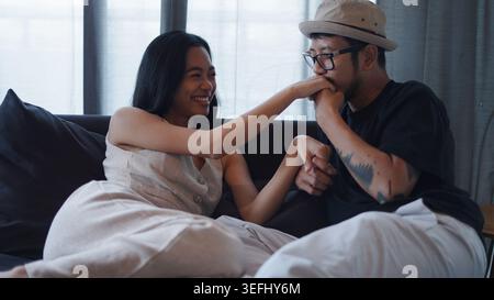Young couple showing affection and intimacy on sofa, man kissing woman's hand Stock Photo