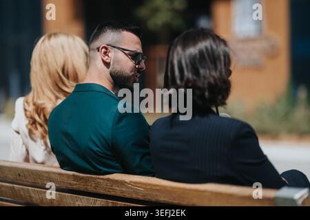Businesspeople having an informal meeting on a bench outside an office building during a break Stock Photo