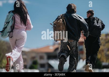 School friends running across campus with backpacks on a sunny day, youthful energy and motion Stock Photo