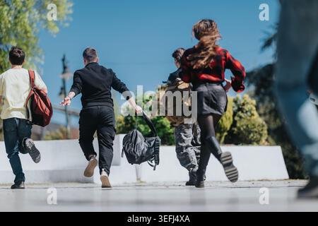 School friends running with backpacks across campus on a sunny day Stock Photo