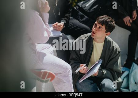 High school students studying and discussing notes outdoors during a group study session Stock Photo