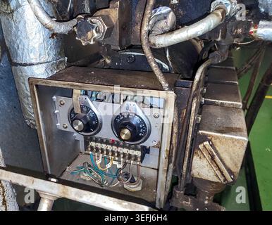 Close-up of mechanical fuel flow and temperature regulating dials with red arrows on an industrial boiler burner system. Stock Photo
