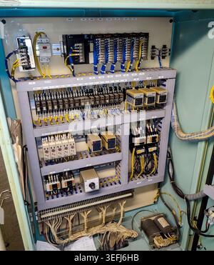 Detailed internal look at complex rows of relays, terminals, electronic controllers, and wiring loops inside a safety control panel. Stock Photo