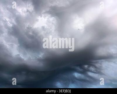 Large swirling storm clouds filling dramatic evening sky with visible birds in distance. Atmospheric weather scene with layered cloud textures and mot Stock Photo