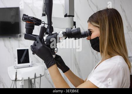 Female Dentist Working With Dental Microscope In Modern Clinic Stock Photo