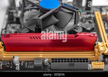 A RAM module installed on a computer motherboard next to a CPU cooling fan. Stock Photo