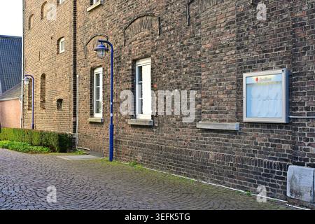 Abteipl, Germany - April 1, 2026: Historic brick church wall with bulletin case and blue lamps Stock Photo
