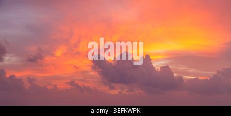 A beautiful sunset sky filled with vivid colors and soft clouds creates a stunning scenic backdrop at dusk. Stock Photo