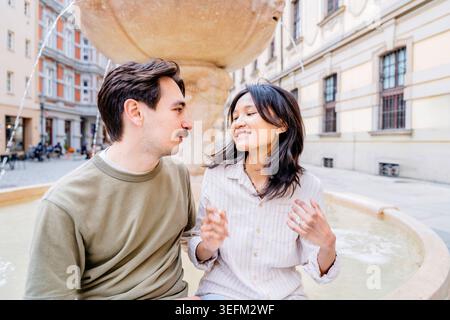 Young interracial couple smiling together near fountain in old city Stock Photo