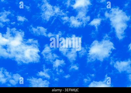 Bright blue sky filled with soft white clouds creating a peaceful natural background with airy texture and dreamy atmosphere. Stock Photo