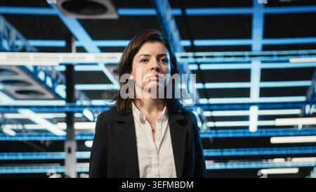Inspecting IT infrastructure, blue wireframe mesh visualization and manager in data center. Digital twin simulation, AR overlay and IT professional walking in server room Stock Photo