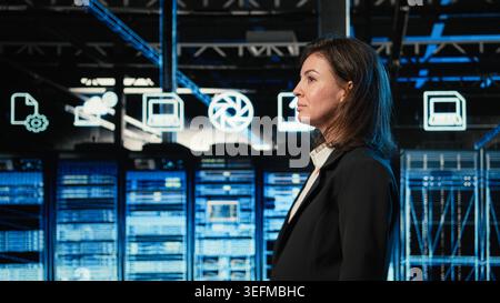 Engineer walking in data center, looking at industrial automation systems digital twin virtualization. Server room IT expert scanning blue wireframe mesh network equipment Stock Photo