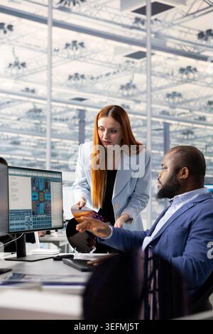 Brainstorming, SoC architecture and female semiconductor engineer with colleague in hardware manufacturing facility office. Researching microelectronic parts, RD and woman with African american man Stock Photo