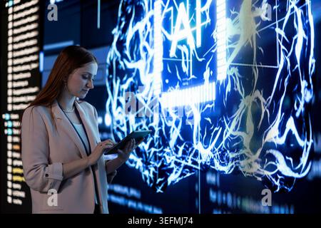 Engineer uses tablet to approve automated AI agent modifications. Software developer offloading code generation to AGI artificial intelligence, streamlining programming tasks Stock Photo