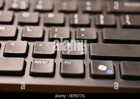 Angled Top View Macro Close-Up Black Computer Keyboard Highlighting Slash and Question Mark Keys on Blurred Tech Backgrounds Stock Photo