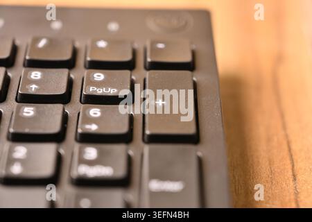 Angled Top View Macro Close-Up Black Computer Keyboard Highlighting Plus Key on Numeric Keypad on Blurred Tech Backgrounds Stock Photo
