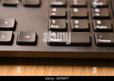 Angled Top View Macro Close-Up Black Computer Keyboard Highlighting Number 0 and Insert Key on Numeric Keypad on Blurred Tech Backgrounds Stock Photo