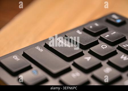 Side Angled Top View Macro Close-Up Black Computer Keyboard Highlighting Caps Lock Key on Blurred Tech Backgrounds Stock Photo