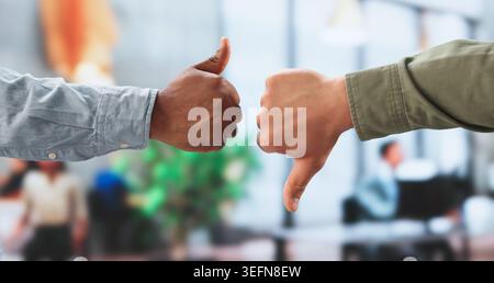 Two Businesspeople Showing Thumbs Up And Down While Discussing Feedback. Stock Photo