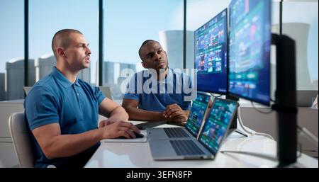 Two Engineers Use SCADA Software On Computers To Monitor Nuclear Plant Controls. Stock Photo
