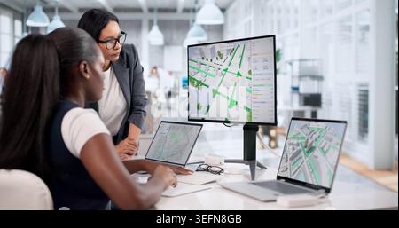 Civil Engineers Review 3D City Road Maps On Laptops For Traffic Planning. Stock Photo