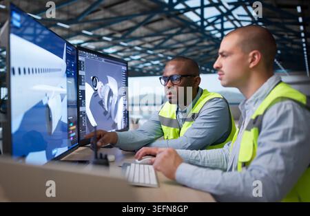 Two Engineers Use 3D Software Designing Airplane Engine Parts Together. Stock Photo