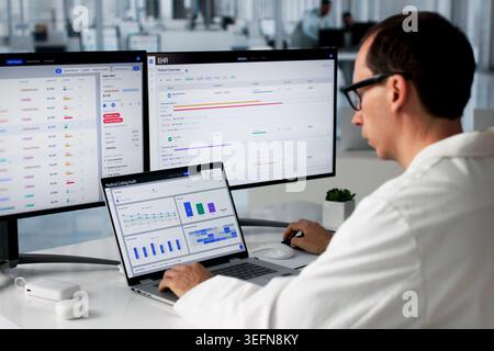 Man Reviews Patient Data On Laptop To Ensure Medical Billing Accuracy. Stock Photo