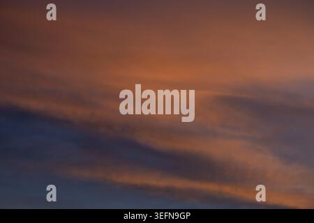 Defocused sunset sky with warm terracotta and burnt orange tones blending into deep blue-grey in soft diagonal bands Stock Photo