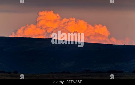 Huge cumulonimbus storm clouds gather over the horizon lit up red by the sunset over dark foreground at Suikerbosrand, Johannesburg  South Africa Stock Photo
