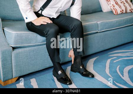 Gentleman preparing for event. Male adjusting shoes in elegant room setting Stock Photo