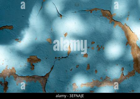 A close up background shot of weathered light blue paint peeling and cracking to reveal damaged concrete texture on an old wall. Stock Photo