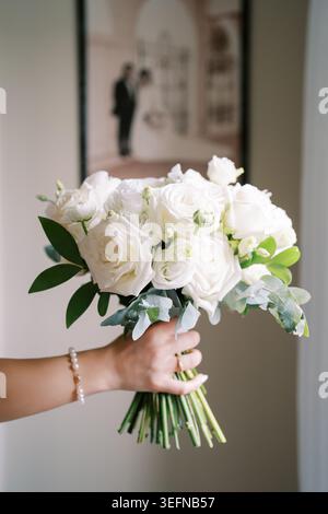 A bridal bouquet of white roses in her hand Stock Photo
