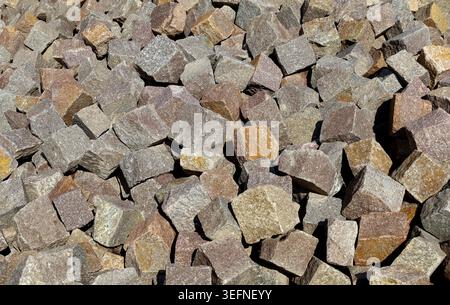 Large heap of porphyry cubes ready to be used for sidewalk or exterior pavement. Construction materials. Background and texture. Stock Photo