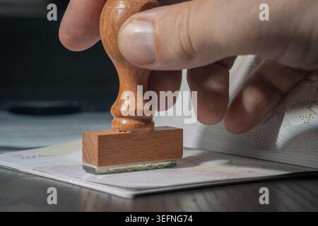 Man's hand is stamping a visa in passport. Close-up view. Stock Photo