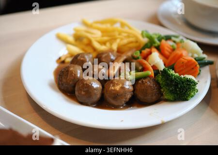 Meatballs, fries and vegetables served on a white plate Stock Photo