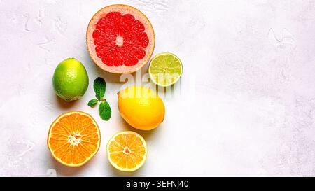 Fresh lemon, orange, grapefruit, lime, green leaves on light background, top view. Citrus Juice Concept, Vitamin C, Fruits. Stock Photo