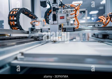 Automated laser cutting machine working on industrial sheet material. Precision laser cutting head processing sheet material on a modern automated pro Stock Photo