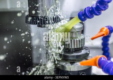 Dynamic close view of CNC machining with coolant splash on metal cutting tool in automated industrial production. Stock Photo
