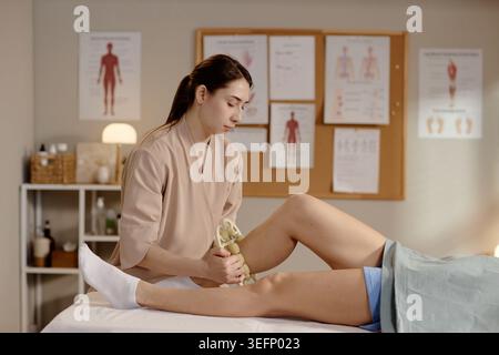 Adult Woman Therapist Massaging Patient Leg during Rehab Session Stock Photo