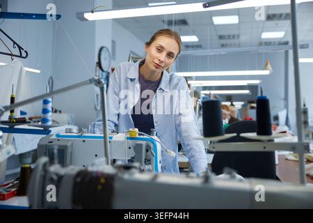 Young seamstress inspecting and ensuring quality of industrial sewing work Stock Photo
