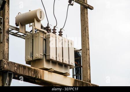 This image features a power transformer mounted on a utility pole, with electrical wires and insulators, showcasing essential electrical infrastructur Stock Photo
