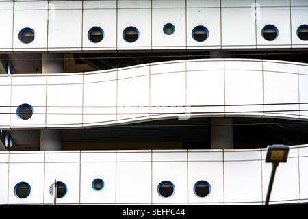 This image showcases the exterior of a modern building featuring a smooth facade with circular windows and a curved balcony, demonstrating contemporar Stock Photo