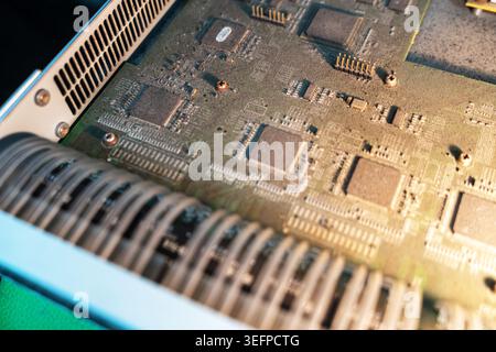 Detailed close-up of a vintage circuit board featuring microchips, resistors, and capacitors, illustrating electronic hardware used in old technology Stock Photo